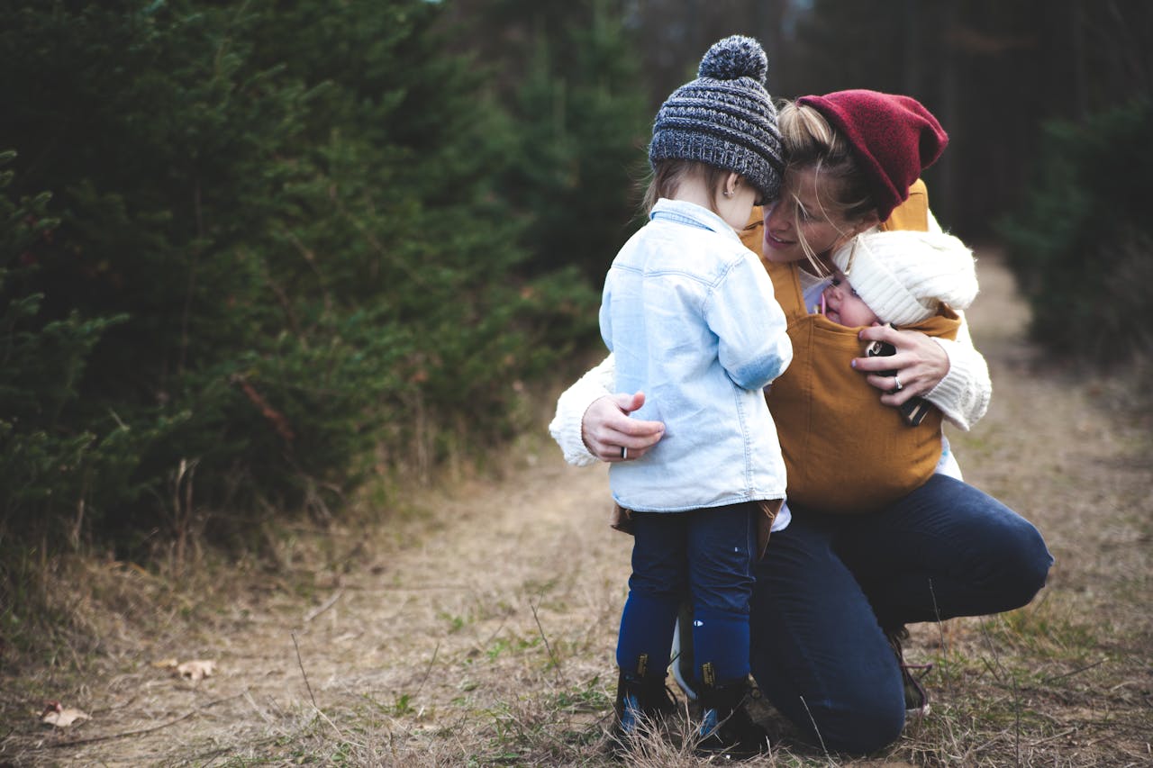 our-experience A loving mother with her two children exploring a forest path during the day.